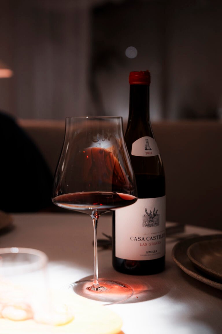 Copa de vino tinto y botella en una mesa de El Portón de Sorní