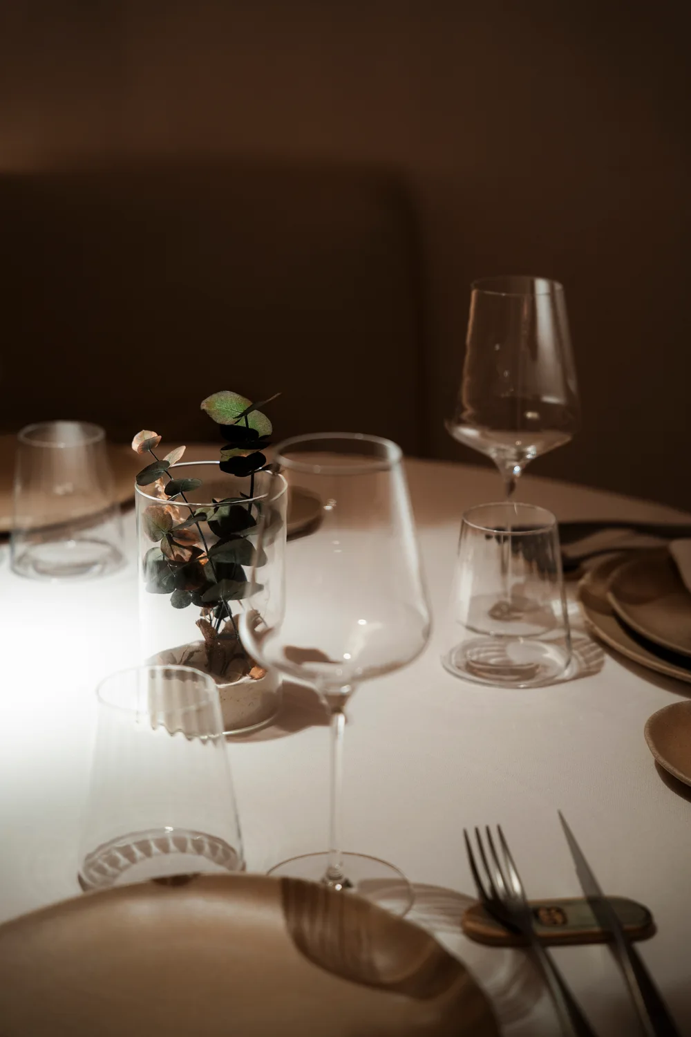 Detalle de copas, platos y flores sobre una mesa del restaurante