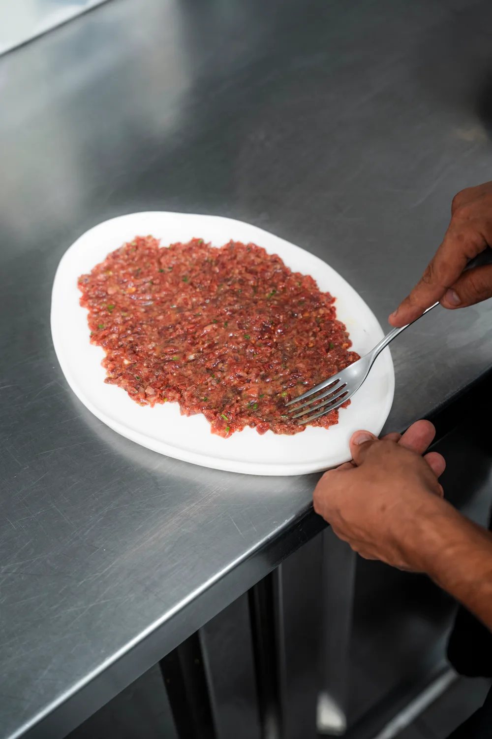 Manos preparando un plato de producto picado en El Portón de Sorní